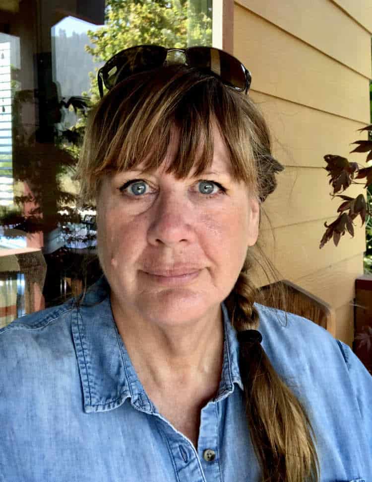 A headshot of a well-dressed person standing in front of a building